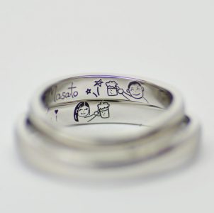ふたりの似顔絵と乾杯シーンを手描き彫刻した結婚指輪